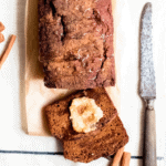 a loaf of cinnamon sweet potato bread sliced with honey butter on top and a knife on the sidec