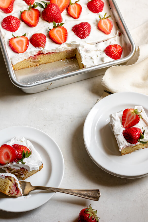 sheet pan with Paleo Strawberry Poke Cake and small plates with slices