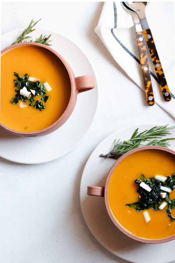 2 bowls of kabocha squash soup on white background