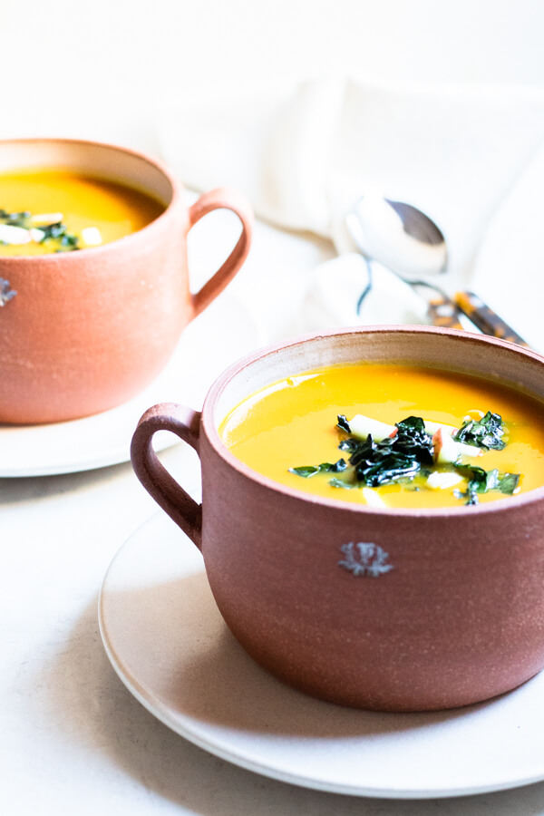 kabocha squash soup in brown bowl on white background