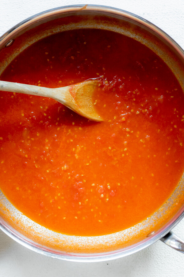 large pan of tomato butter sauce with wooden spoon