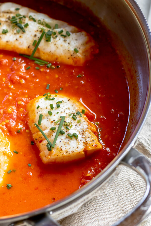 One Pan Cod in Tomato Butter Sauce in a pan simmering in tomato broth