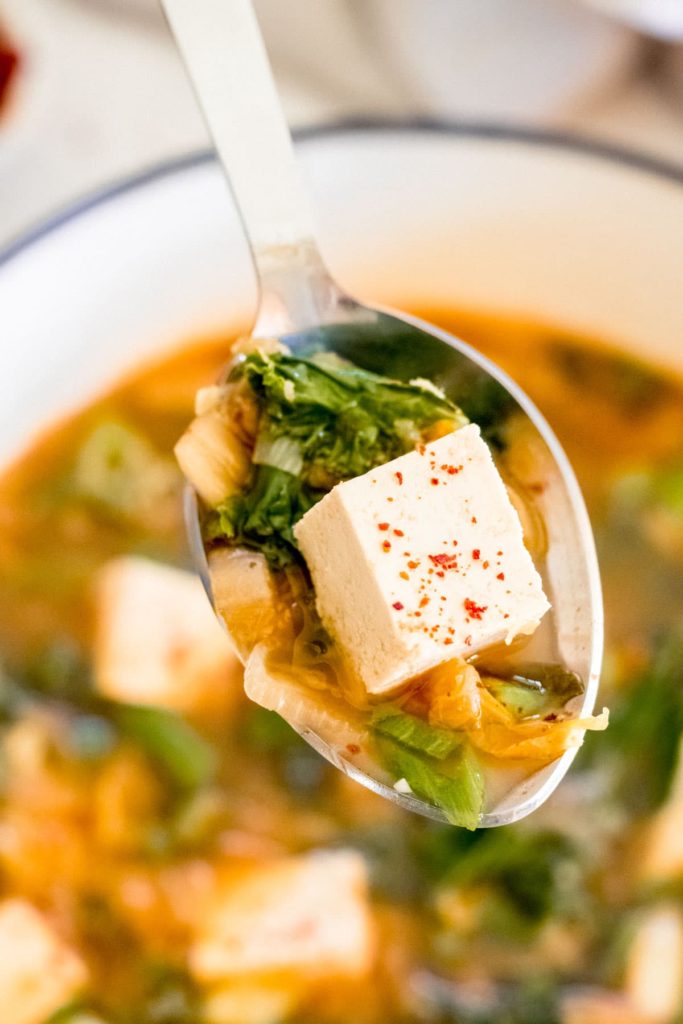 tofu and kale soup on a spoon