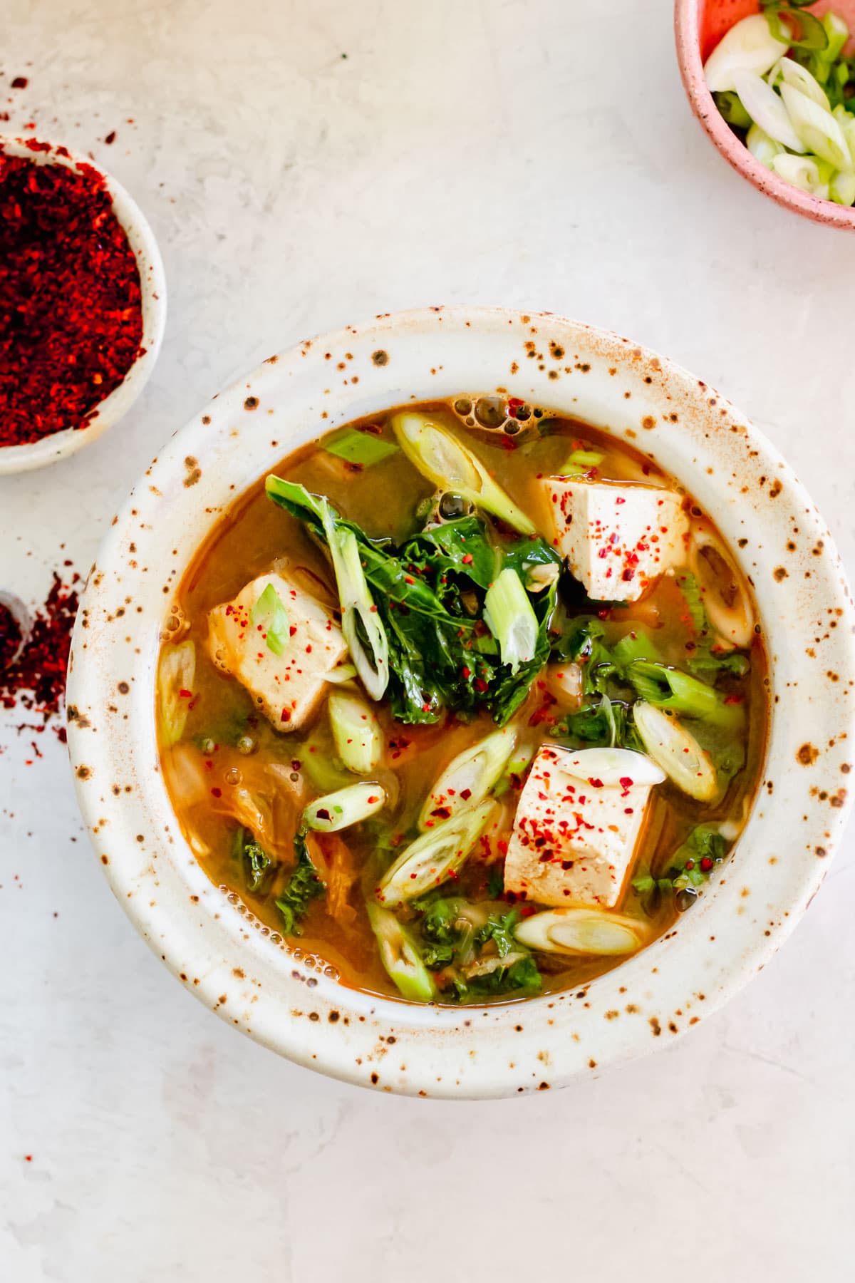 bowl of tofu and kale soup on white background