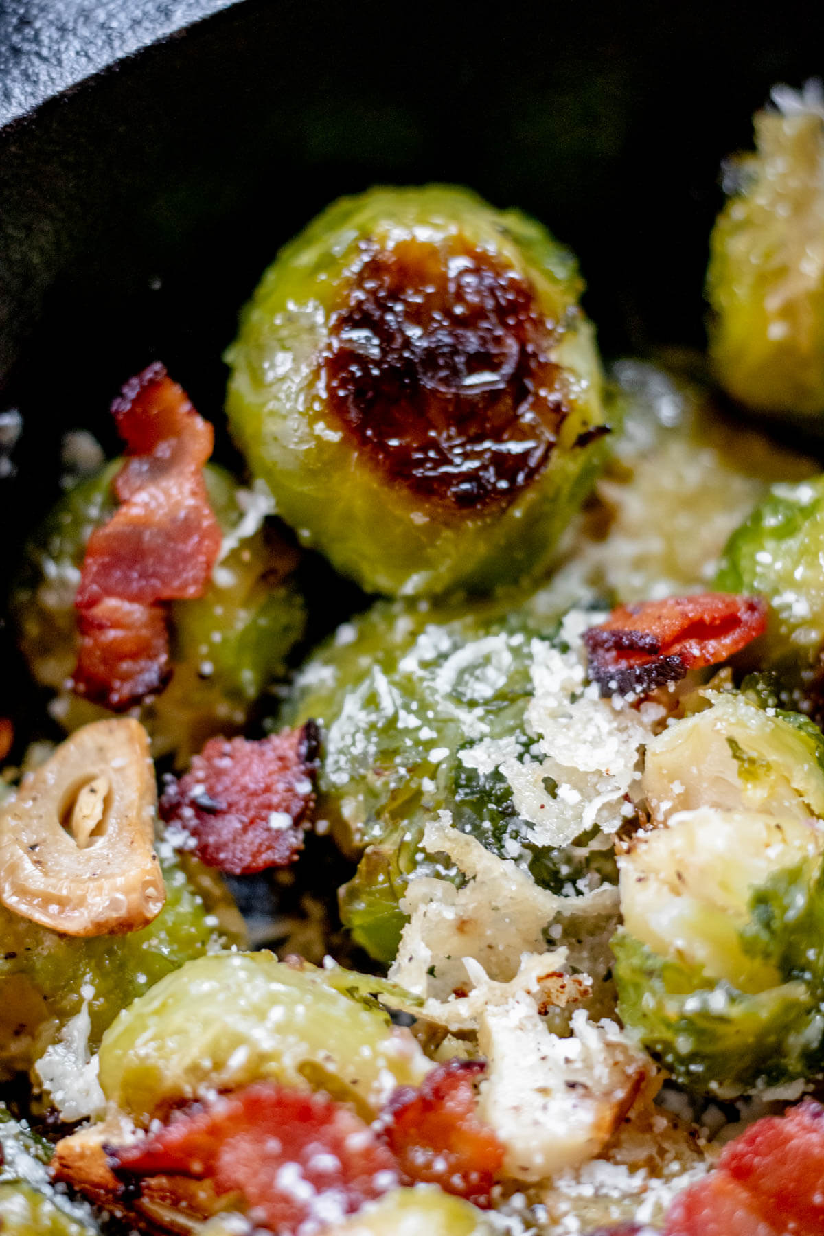 crispy brussels sprout covered in parmesan cheese with crisp garlic and crispy bacon