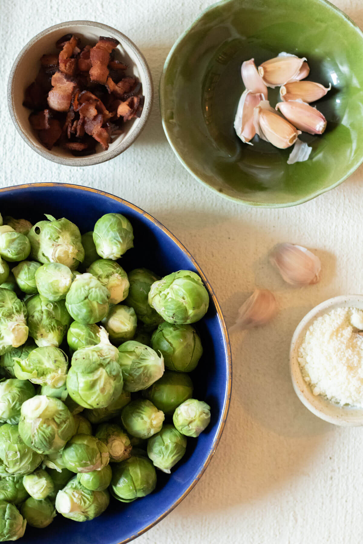 Ingredients needed for large cast iron pan on white background with Oven Roasted Smashed Brussels Sprouts with Bacon and Parmesan