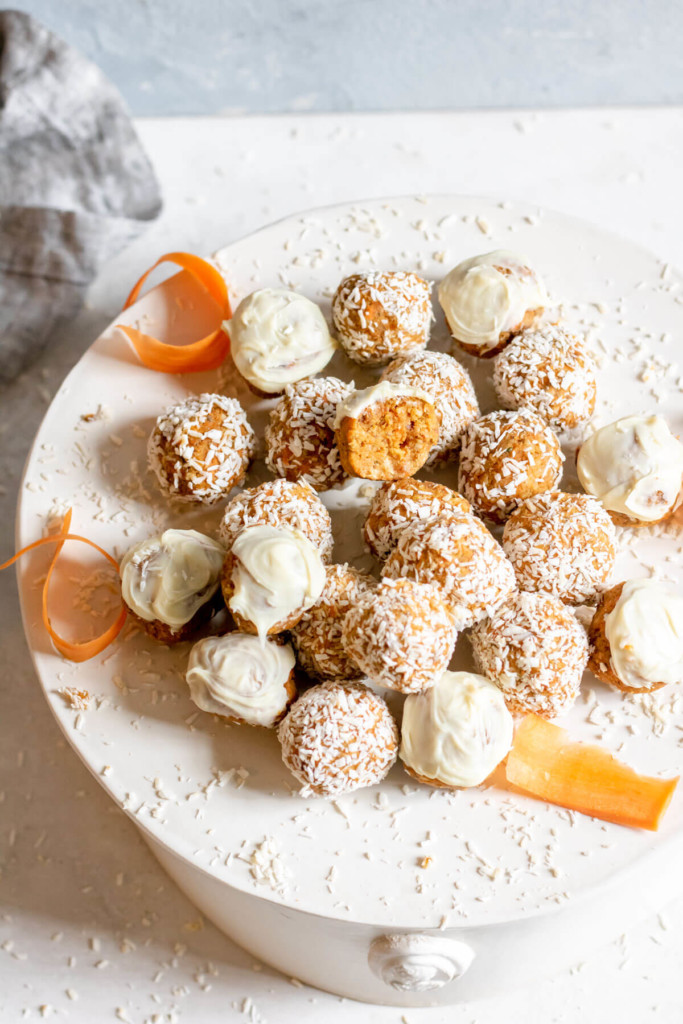 mini carrot cake bites rolled in coconut sitting on a white cake tray on a white background