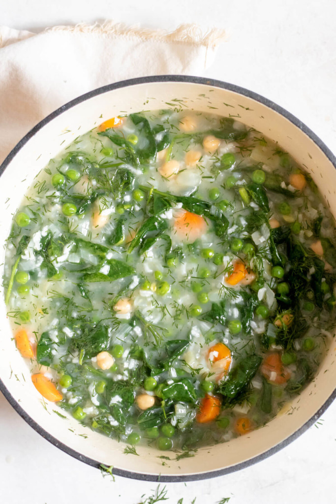 adding vegetables to a lemon rice soup