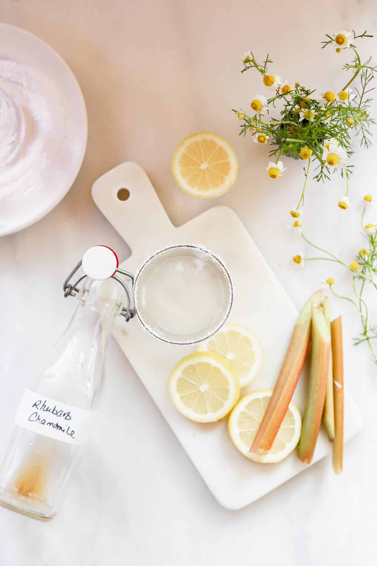lemon, rhubarb, and fresh chamomile flowers on a white background