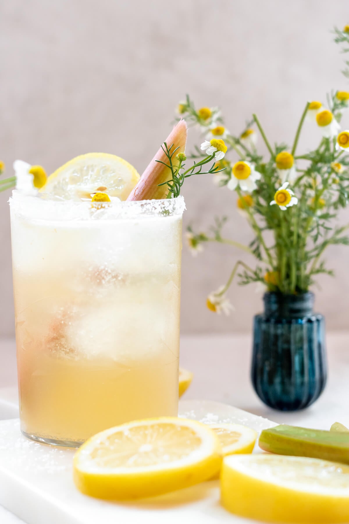 clear glass filled with rhubarb chamomile margarita with fresh lemon