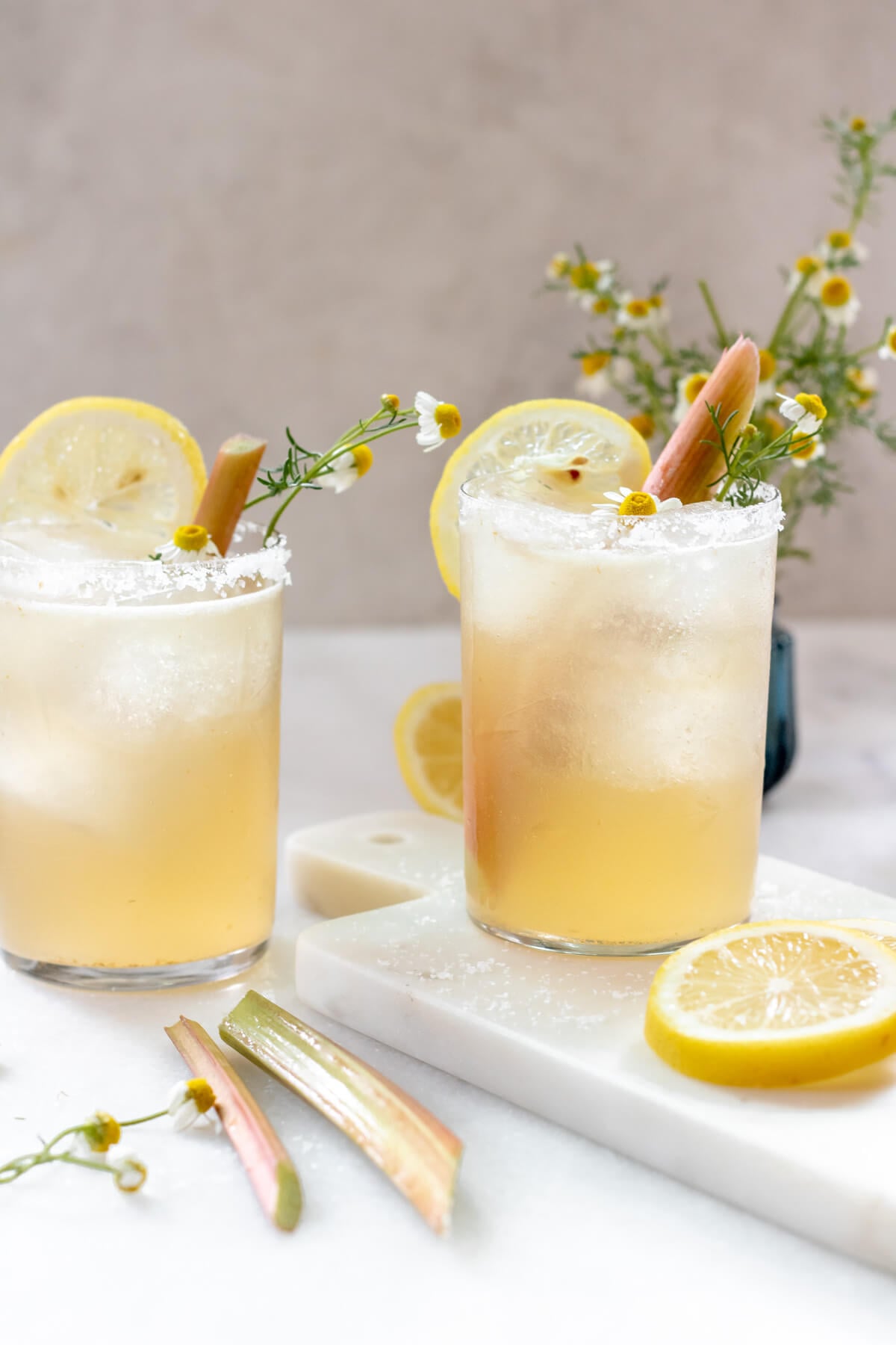 2 glasses filled with rhubarb chamomile margarita and garnished with lemon and rhubarb