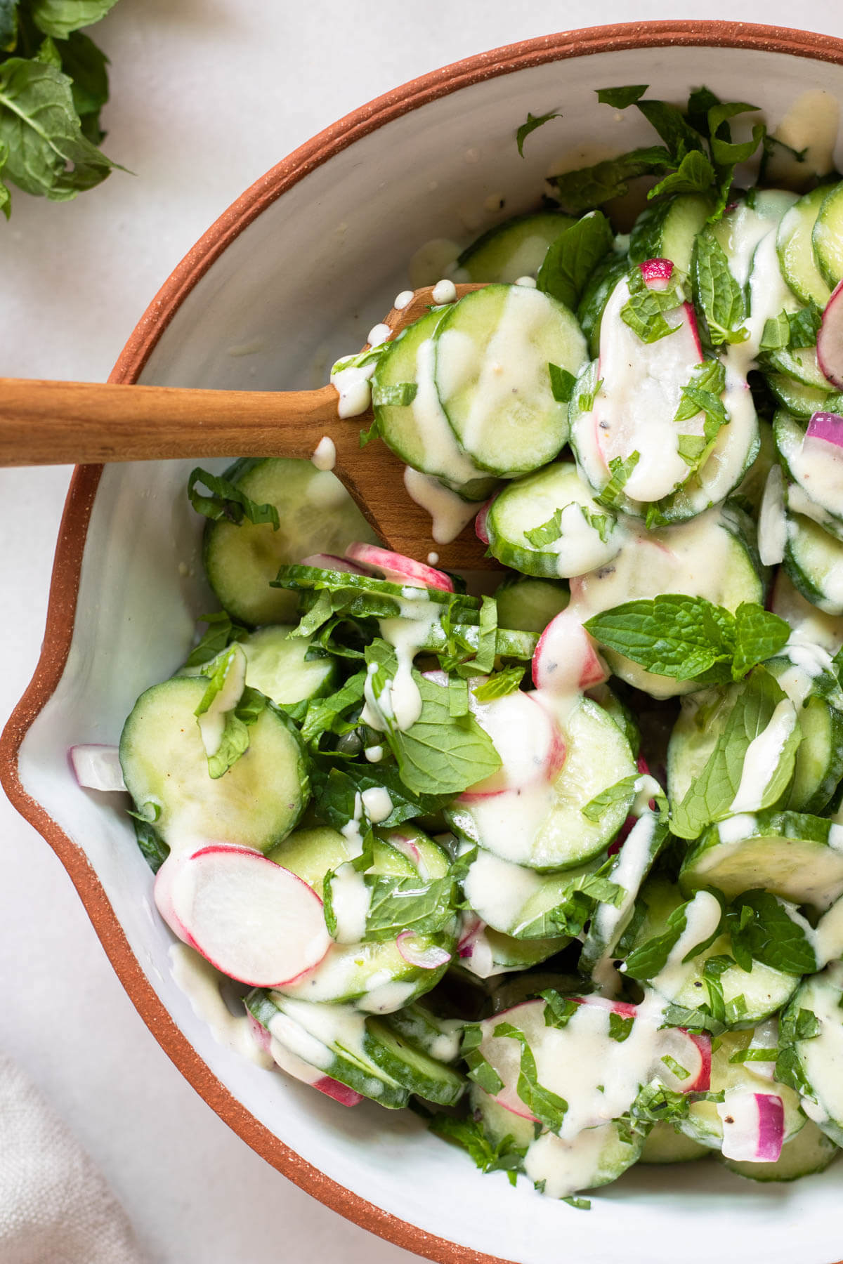close up shot of cucumber and radish salad in a white bowl