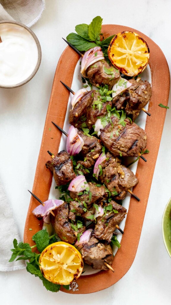 Large platter of grilled lamb kebabs on white background