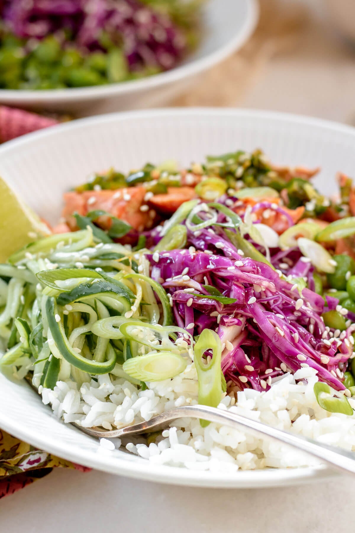 close up shot of a fork in a bowl of rice and vegetables with salmon