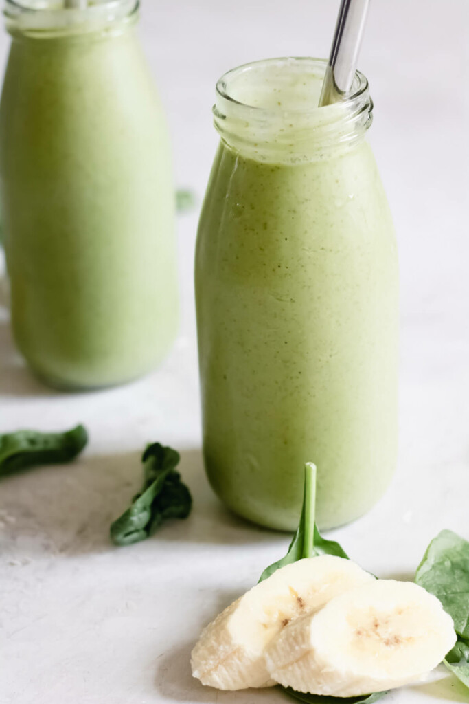 2 jars of green smoothie on white background