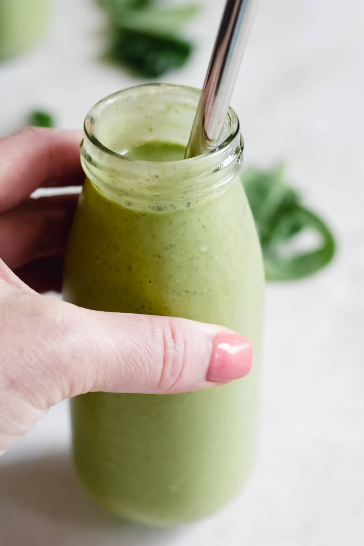 hand holding small jar filled with green smoothie