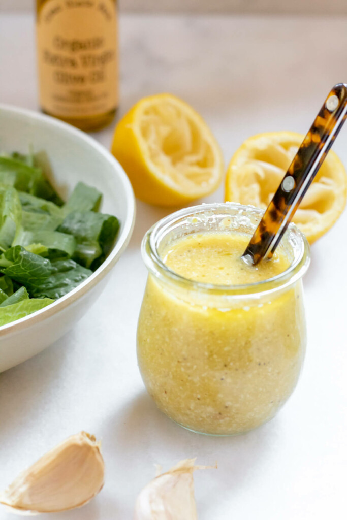 Healthy Caesar salad dressing in glass bowl with salad in the background