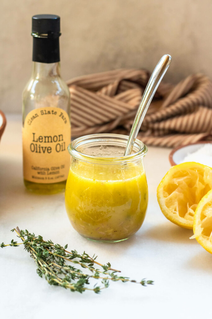lemon thyme salad dressing in a glass jar on a white background