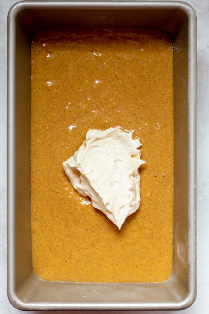 process shot of a dollop of cream cheese on top of pumpkin bread batter