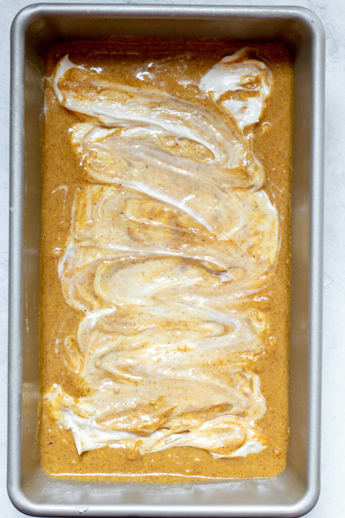 process shot of cream cheese swirled into pumpkin brad
