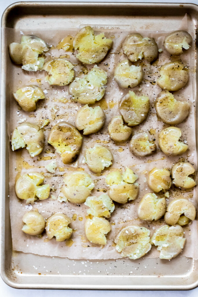 sheet tray with brown parchment paper and potatoes smashed