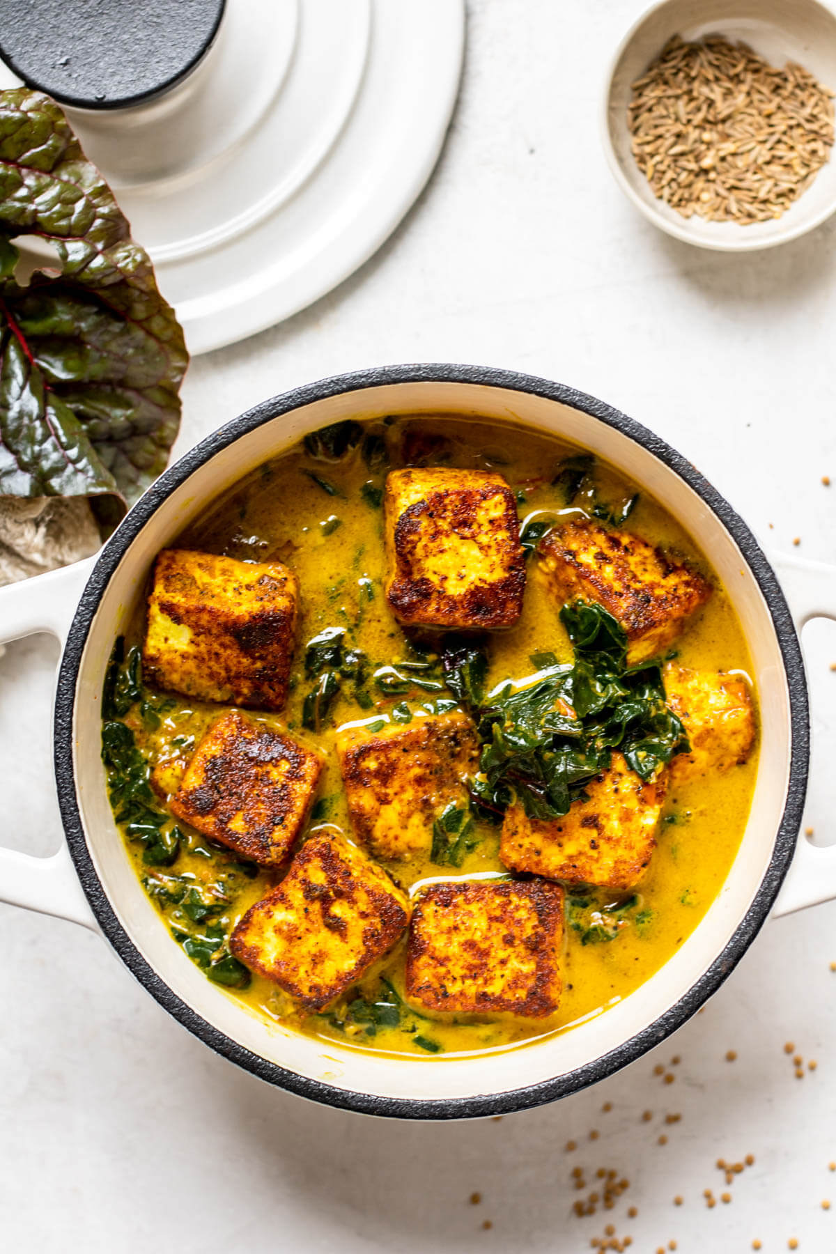 white pot of swiss chard saag paneer on white background