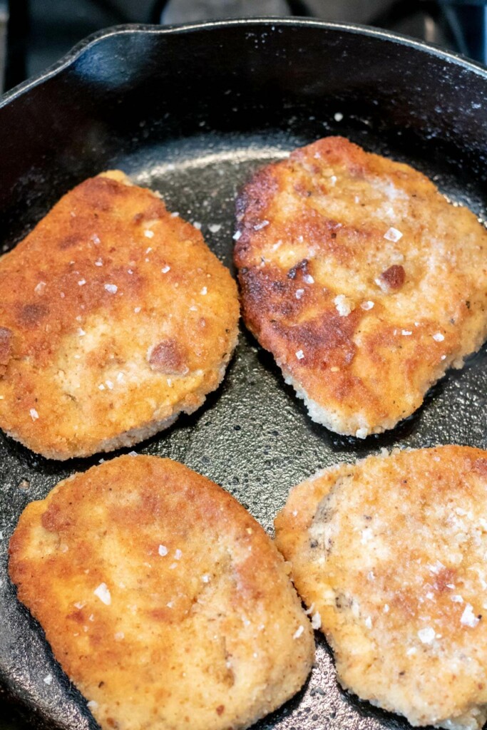 4 pan fried crispy pork cutlet in a cast iron skillet