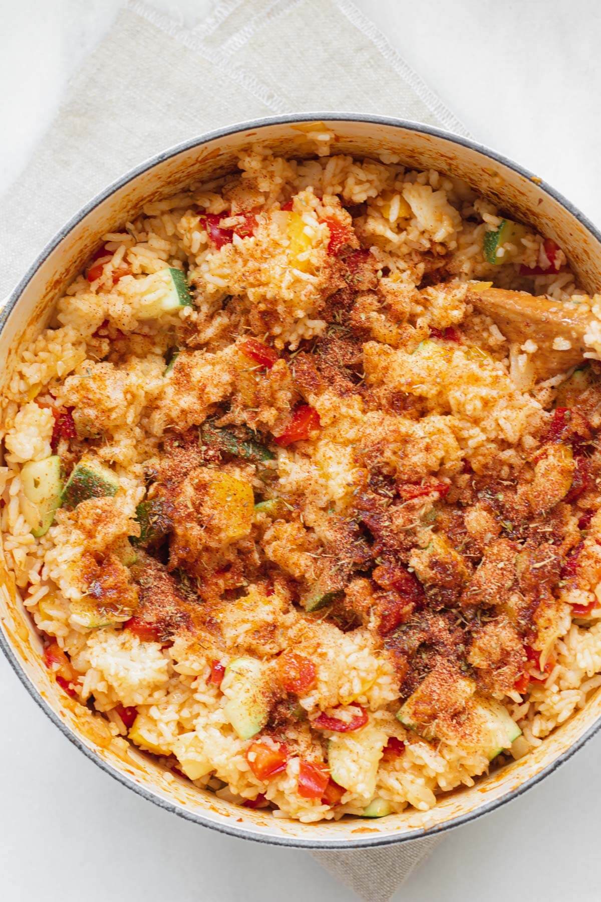 adding more cajun seasoning to cajun shrimp and rice skillet
