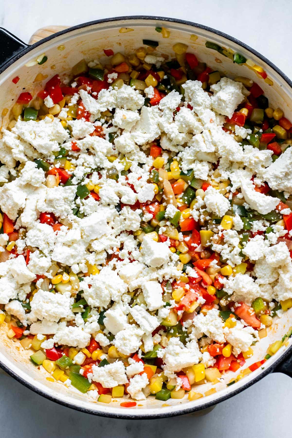 large pan of finely diced veggies with queso fresco on top, calabacitas