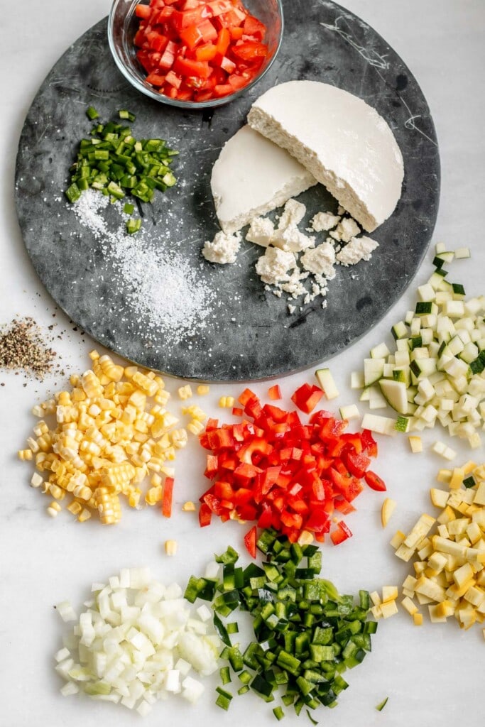 finely diced vegetables on a white background with queso fresco