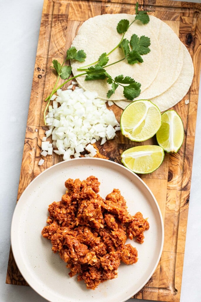 chorizo, onion, lime, and tortilla on a cutting board, ingredients for chorizo tacos