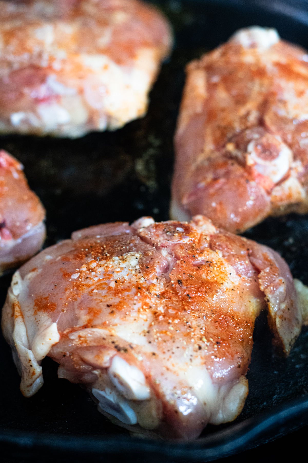 4 chicken thighs in a skillet preparing to cook