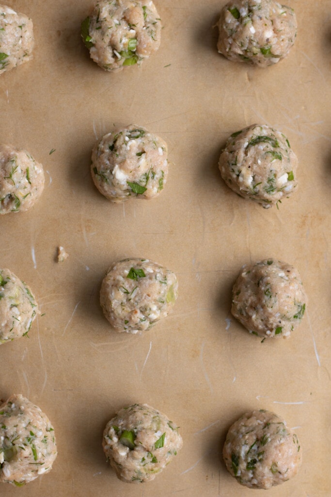 a row of meatballs on a sheet tray