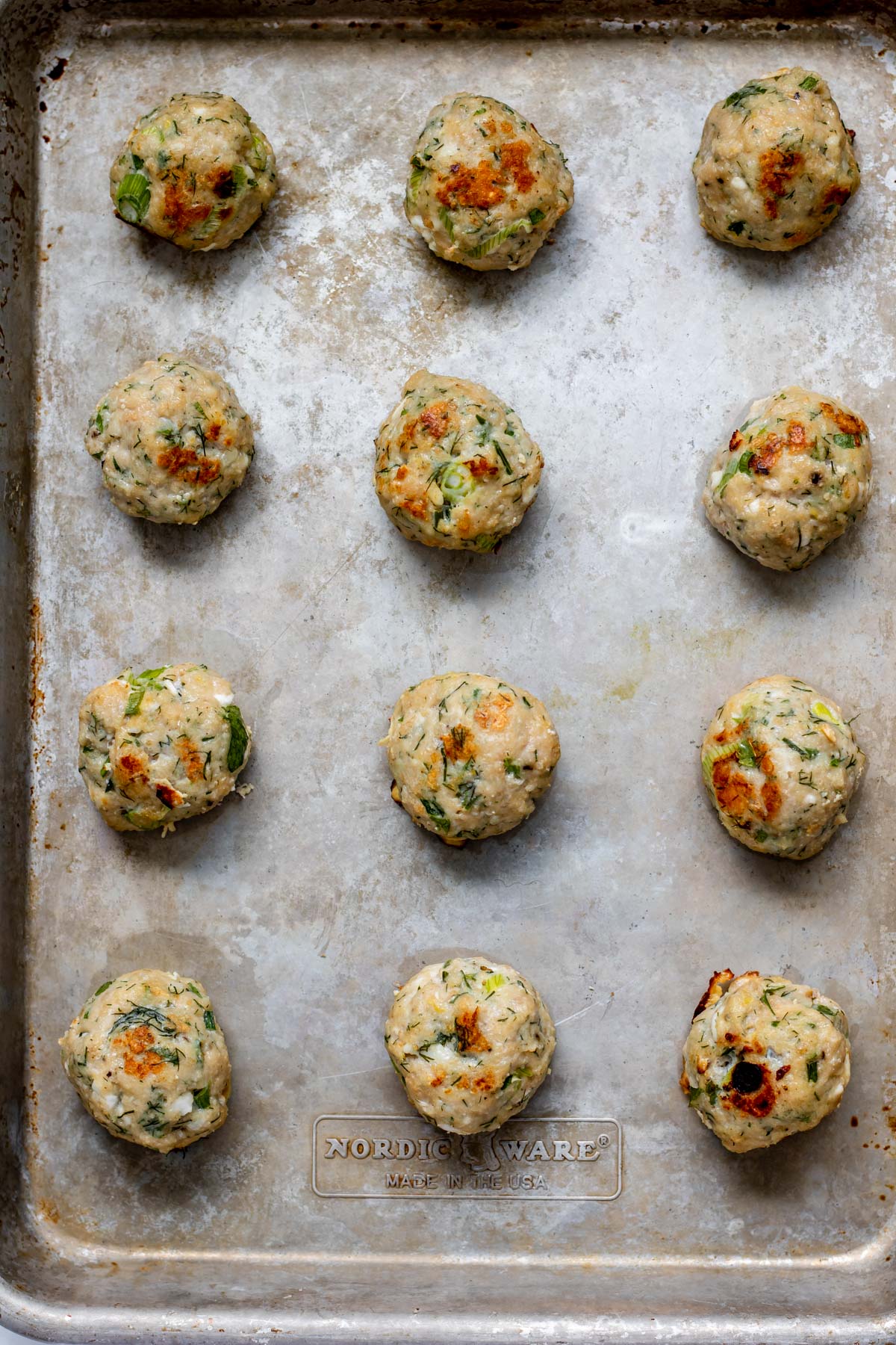 A sheet pan of crispy oven roasted greek chicken meatballs