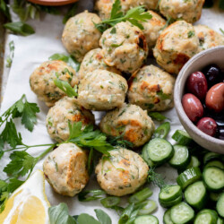 a tray full of greek chicken meatballs and cucumbers, dill, and yogurt sauce