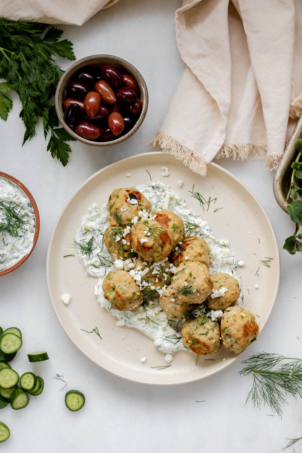 a plate of greek meatballs with a side bowl of olives