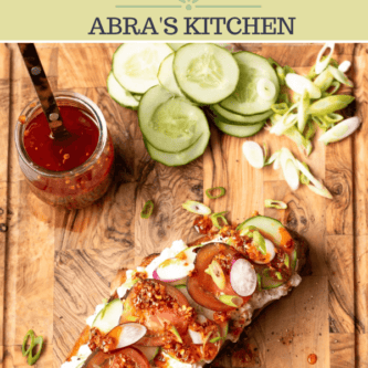 Photo of cottage cheese toast with veggies and chili crunch on a cutting board with the caption "abras kitchen chili crunch cottage cheese toast"