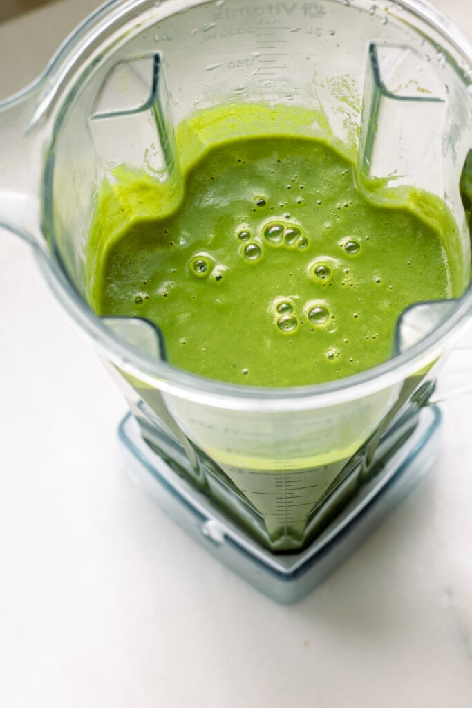 A blender full of bright green creamy broccoli soup
