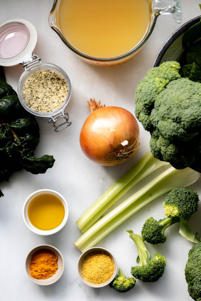 A variety of ingredients on a white background including broccoli, kale, onion, and spices