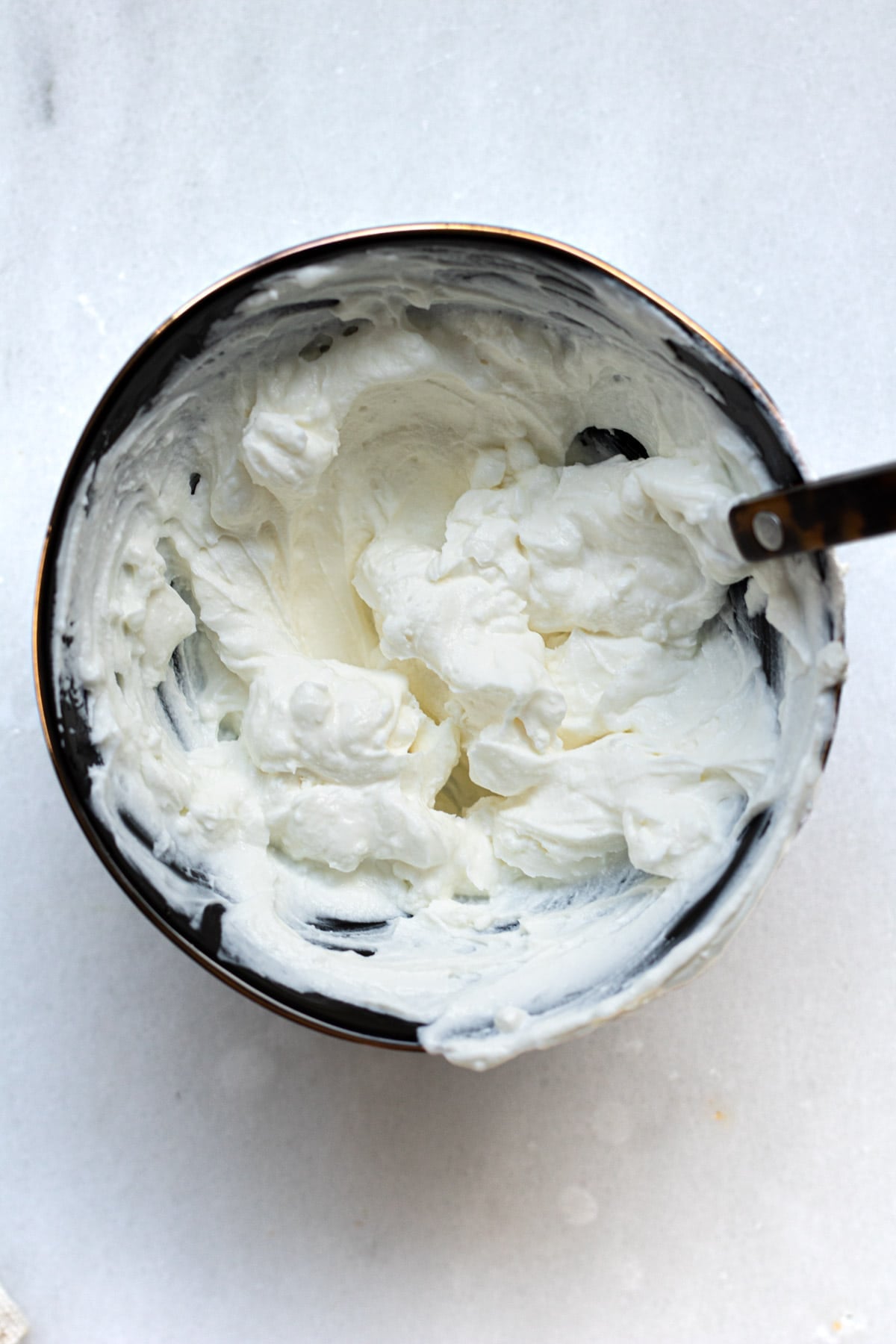 black bowl on white background filled with creamy goat cheese labneh