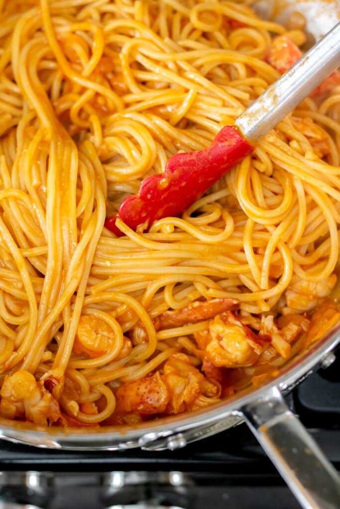 A large pot of spaghetti with a creamy tomato sauce and thick chucks of tender lobster