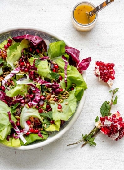 Large bowl of radicchio salad on a white background with mint and pomegranate