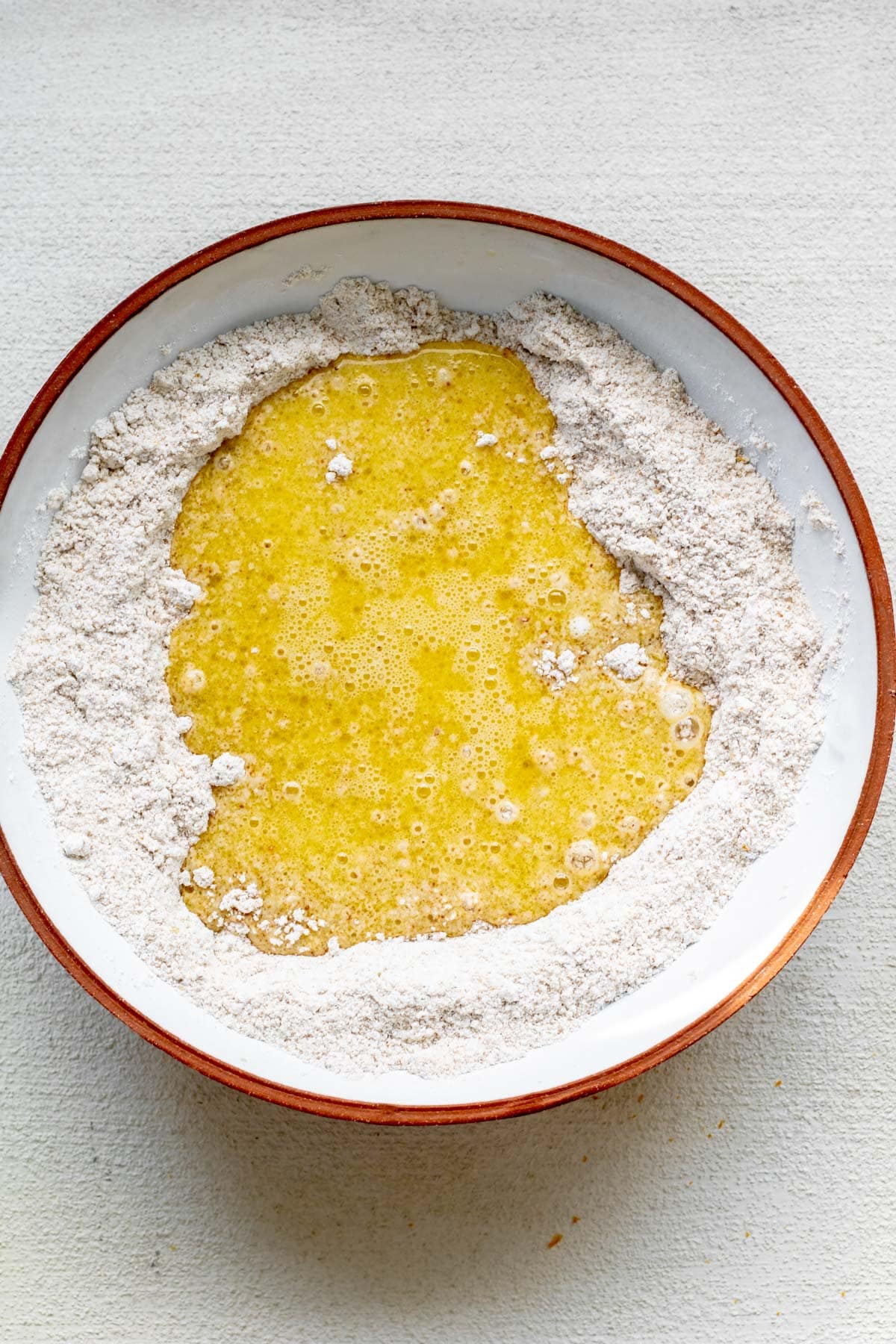 pouring wet ingredients into dry ingredients for gluten free orange muffins