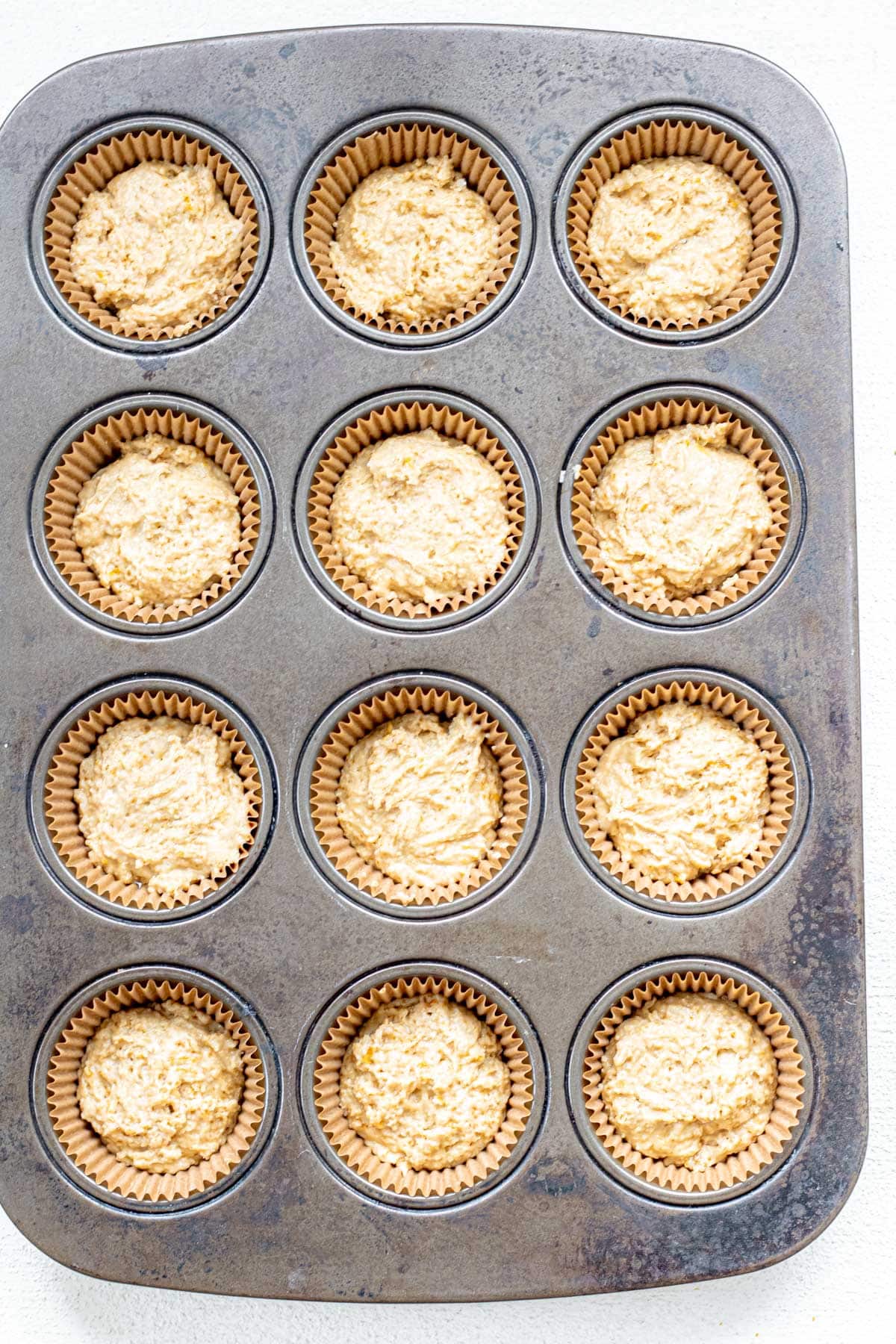 muffin tray filled with gluten free orange muffin batter