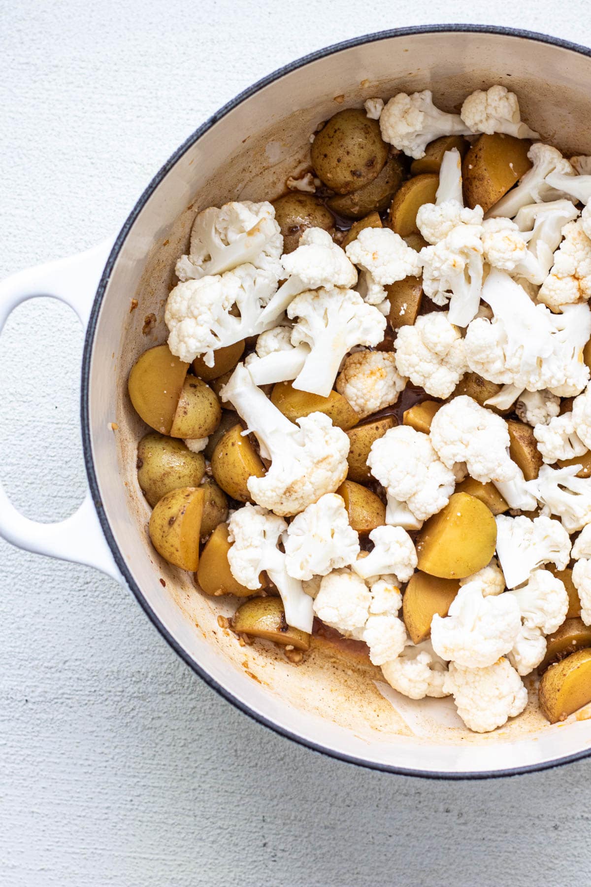 cauliflower florets added to a pot of potatoes