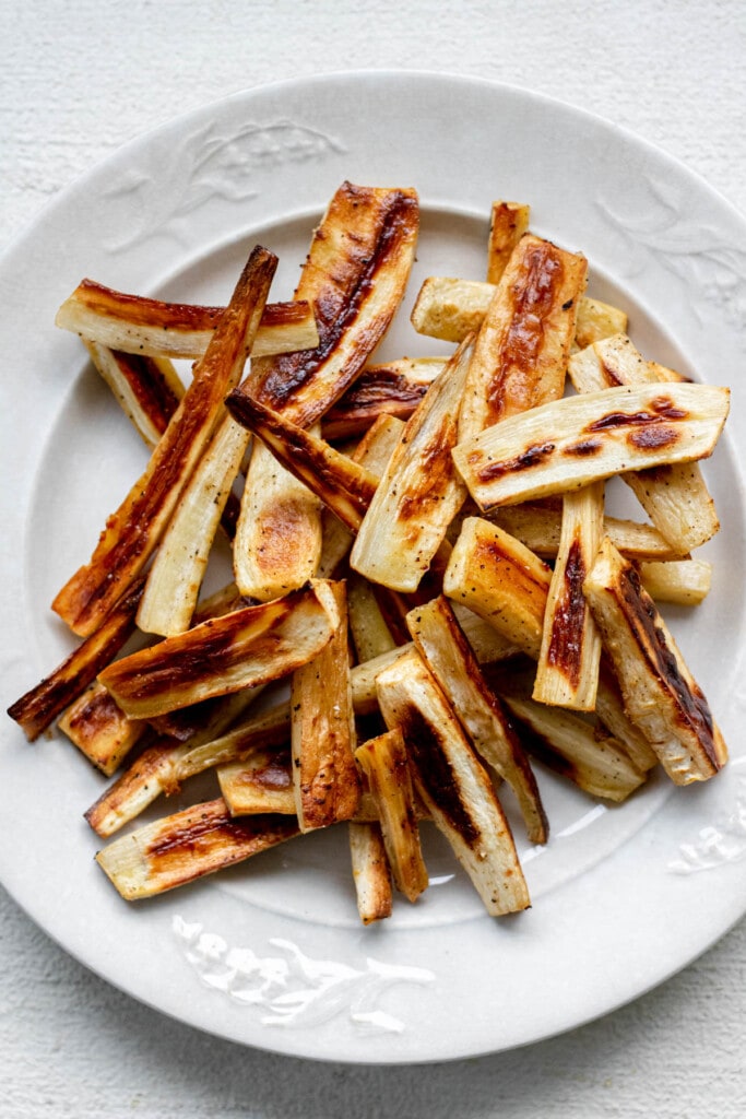 A white plate piled high with roasted parsnips