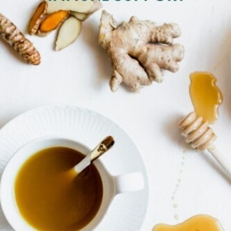 a cup of tea beside ginger, turmeric and honey