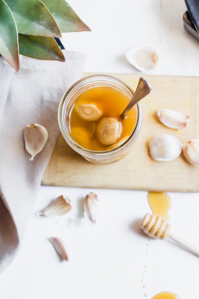 mason jar of honey fermented garlic with spoon holding garlic