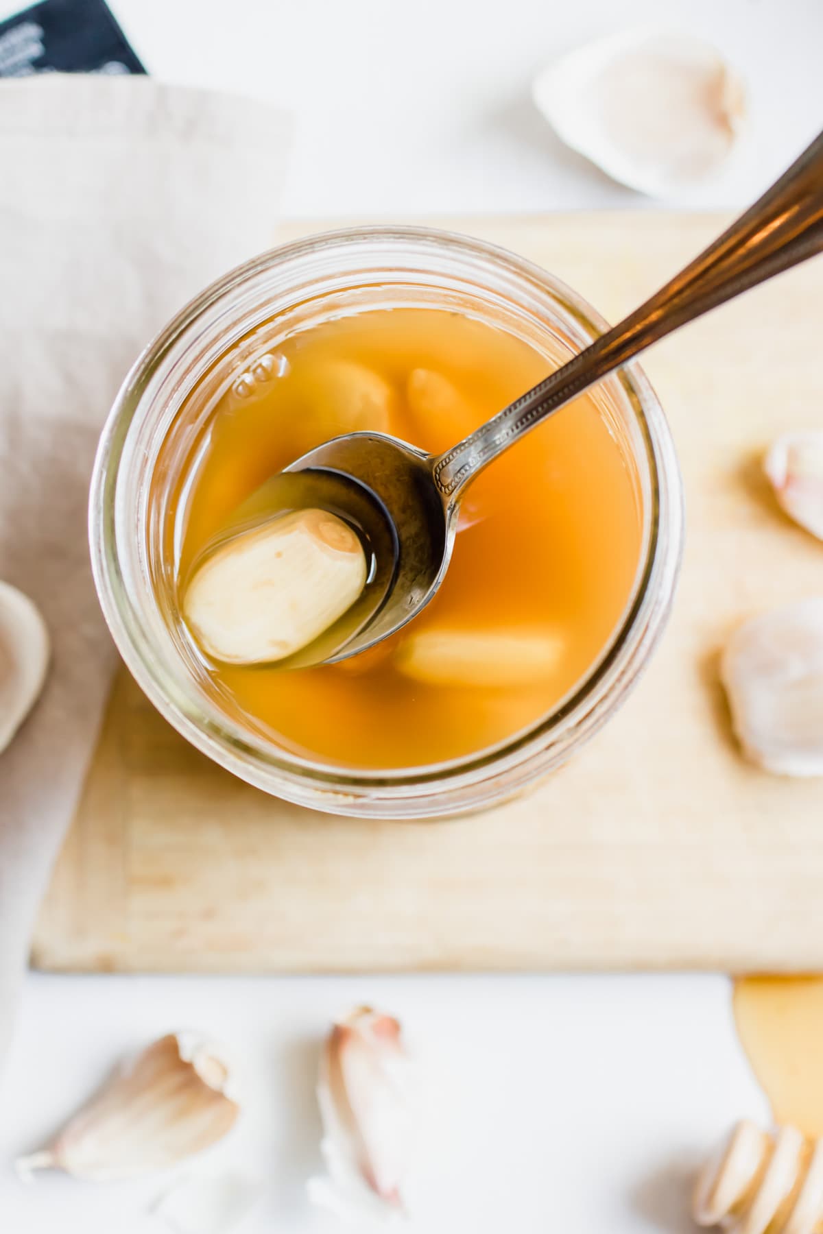 mason jar of honey fermented garlic with spoon holding garlic