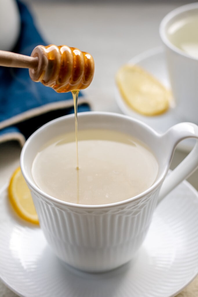 honey dripping into a mug of lemon ginger tea